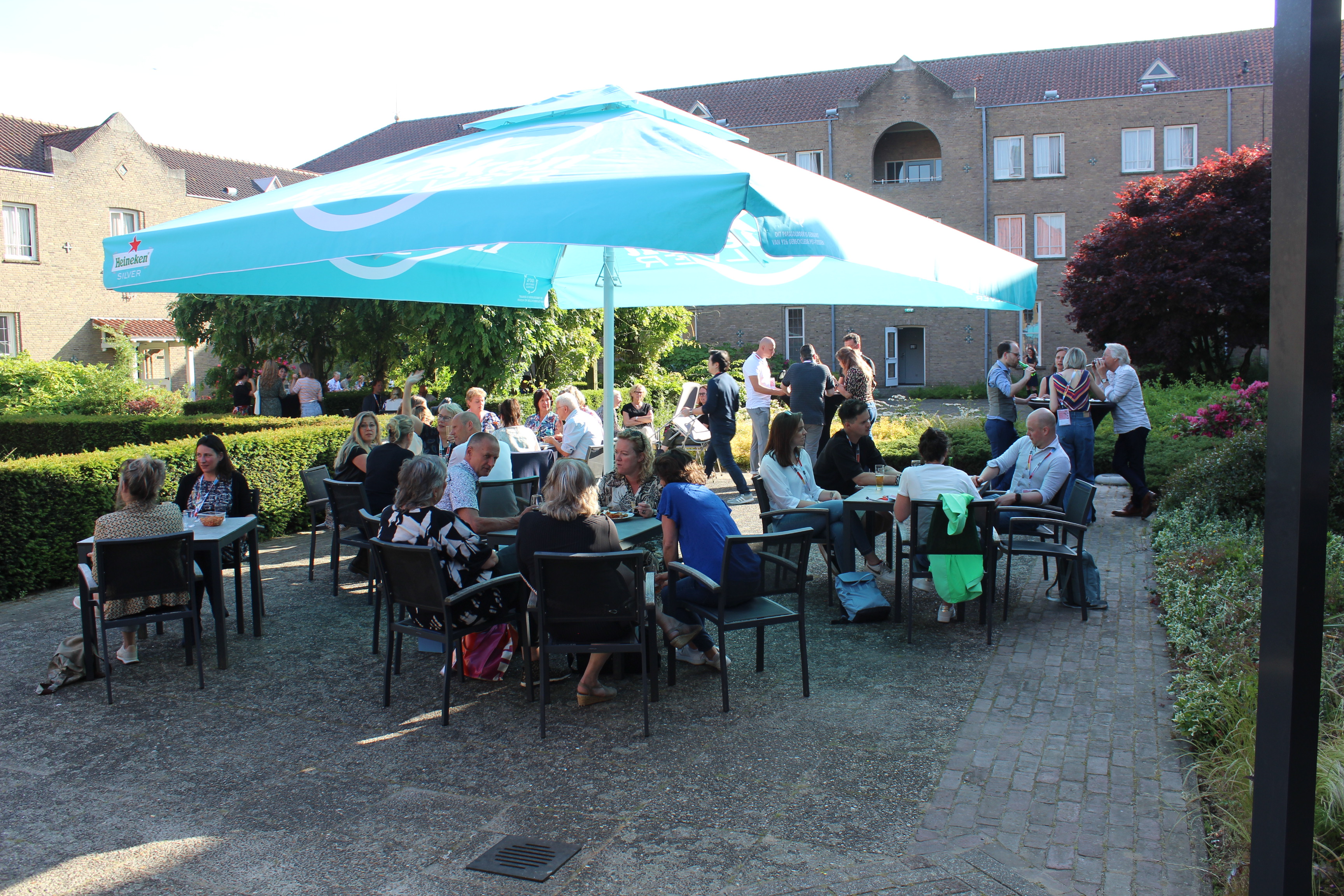 A busy outdoor Page One reception beneath turquoise umbrellas.